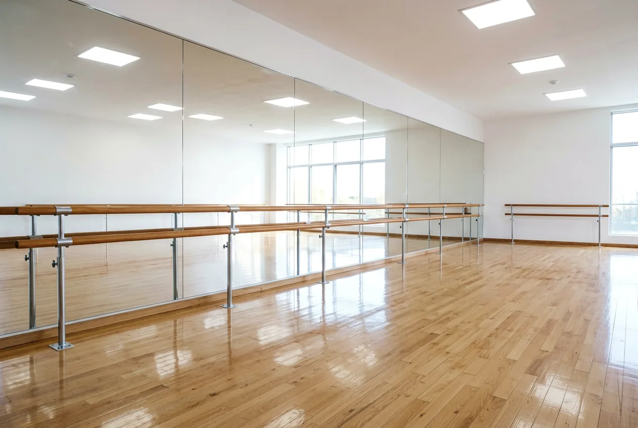 Der leere Tanzraum mit Spiegelwand und Barre, warmes Licht von der Fensterfront