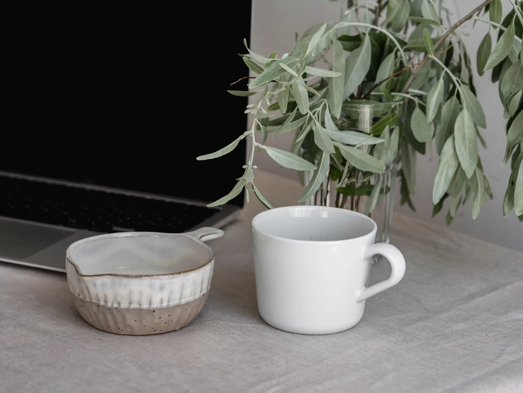 Ruhiger Arbeitsplatz mit Notizbuch, Tasse und Olivenzweig